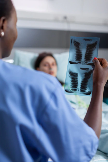 Radiographer holding printed X-ray film from digitizer machine at diagnostic facility in Lekki Lagos